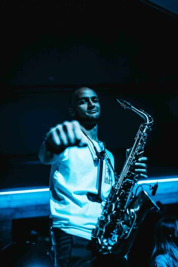 Victor, the saxophonist for Body Funk, extending a hand for a fist bump while holding his saxophone.